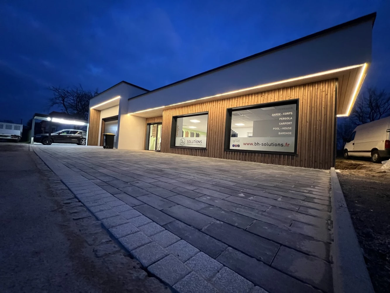 Façade du showroom BH Solutions éclairée par un bandeau LED à la tombée de la nuit