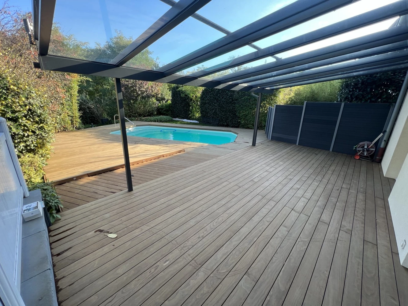 Terrasse en Kebony® sous véranda avec vue sur la piscine à Bischwiller – BH Solutions